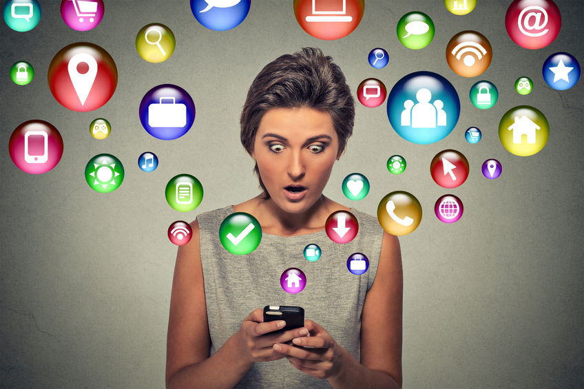 closeup surprised young woman using texting on smartphone with social media application symbols icons flying out of screen.