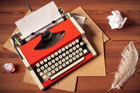 red vintage typewriter with white blank paper sheet