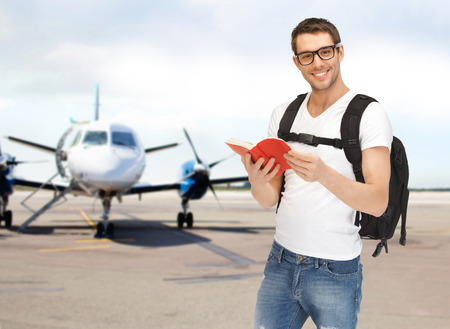 smiling student with backpack and book at airport