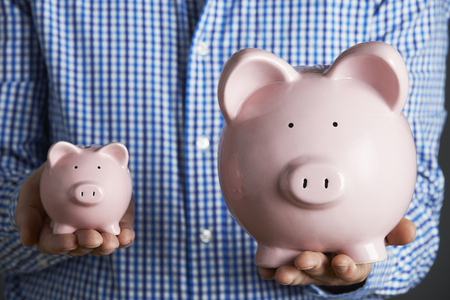 man holding large and small piggy bank concept for biggest scholarships blog